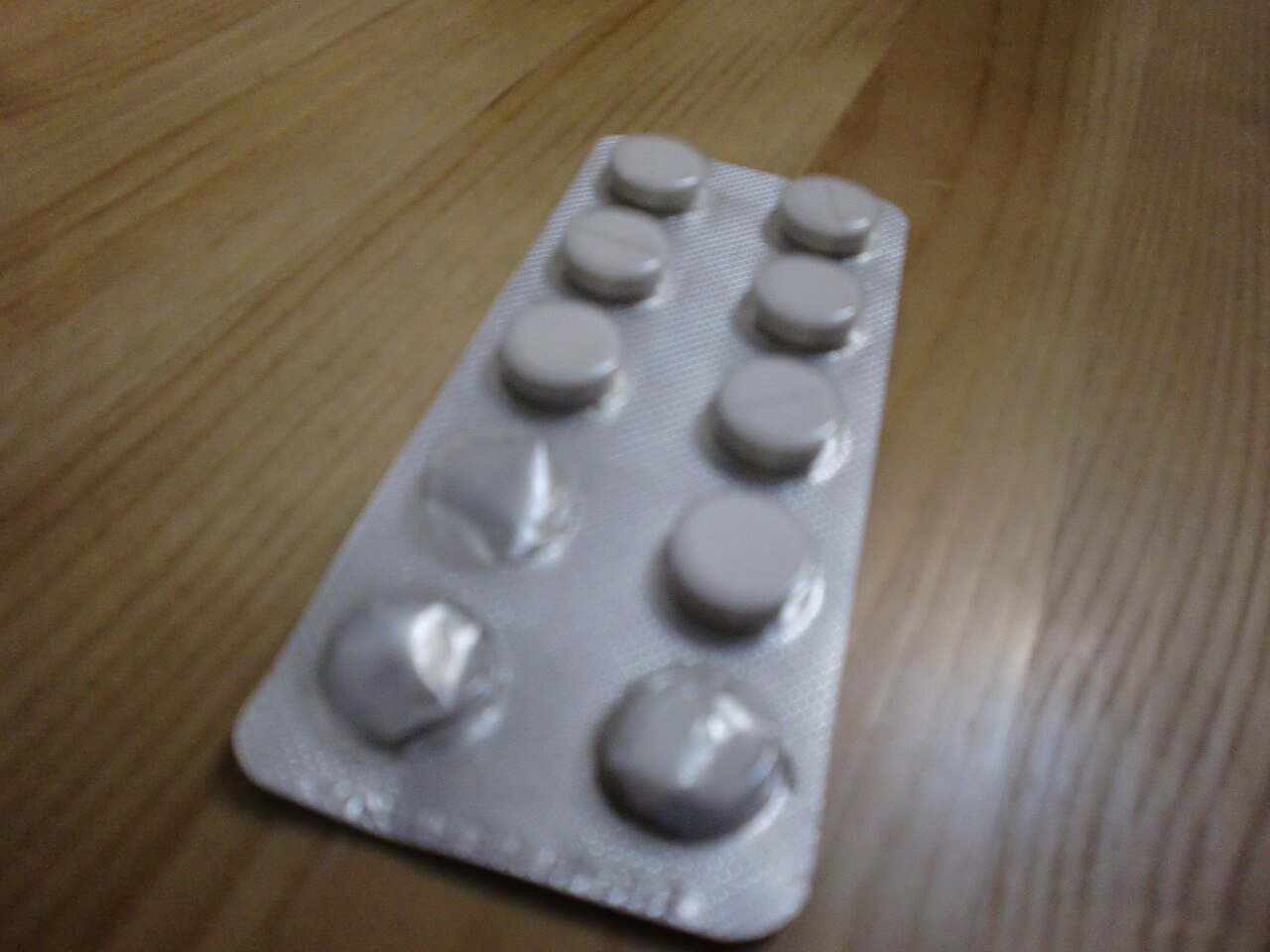 Silver blister pack of white round supplement tablets on wood